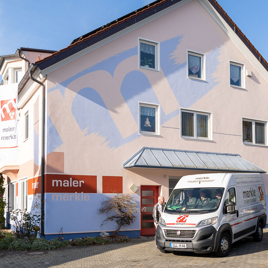 Das Geschäftshaus von Maler Merkle in Illertissen mit Lieferwagen, während Markus Merkle im Gespräch mit Mitarbeitern die nächsten Aufträge plant.