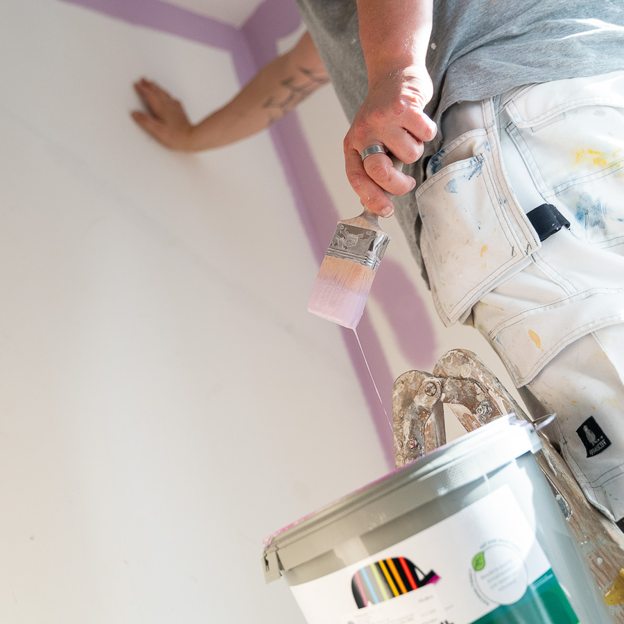 Mitarbeiter von Maler Merkle Illertissen führt Malerarbeiten aus und taucht den Pinsel in Farbe für eine hochwertige Wandgestaltung.