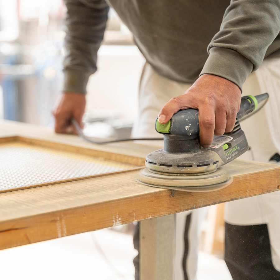 Ein Mitarbeiter von Maler Merkle Illertissen schleift eine Wohnungstür fachgerecht im Rahmen der Zusatzleistungen.