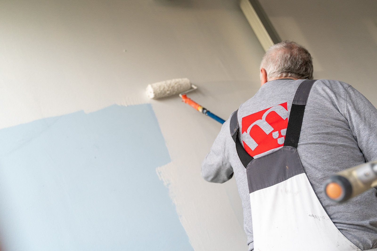  Ein Mitarbeiter von Maler Merkle Illertissen streicht eine Wand fachgerecht bei einem Kundenprojekt. 