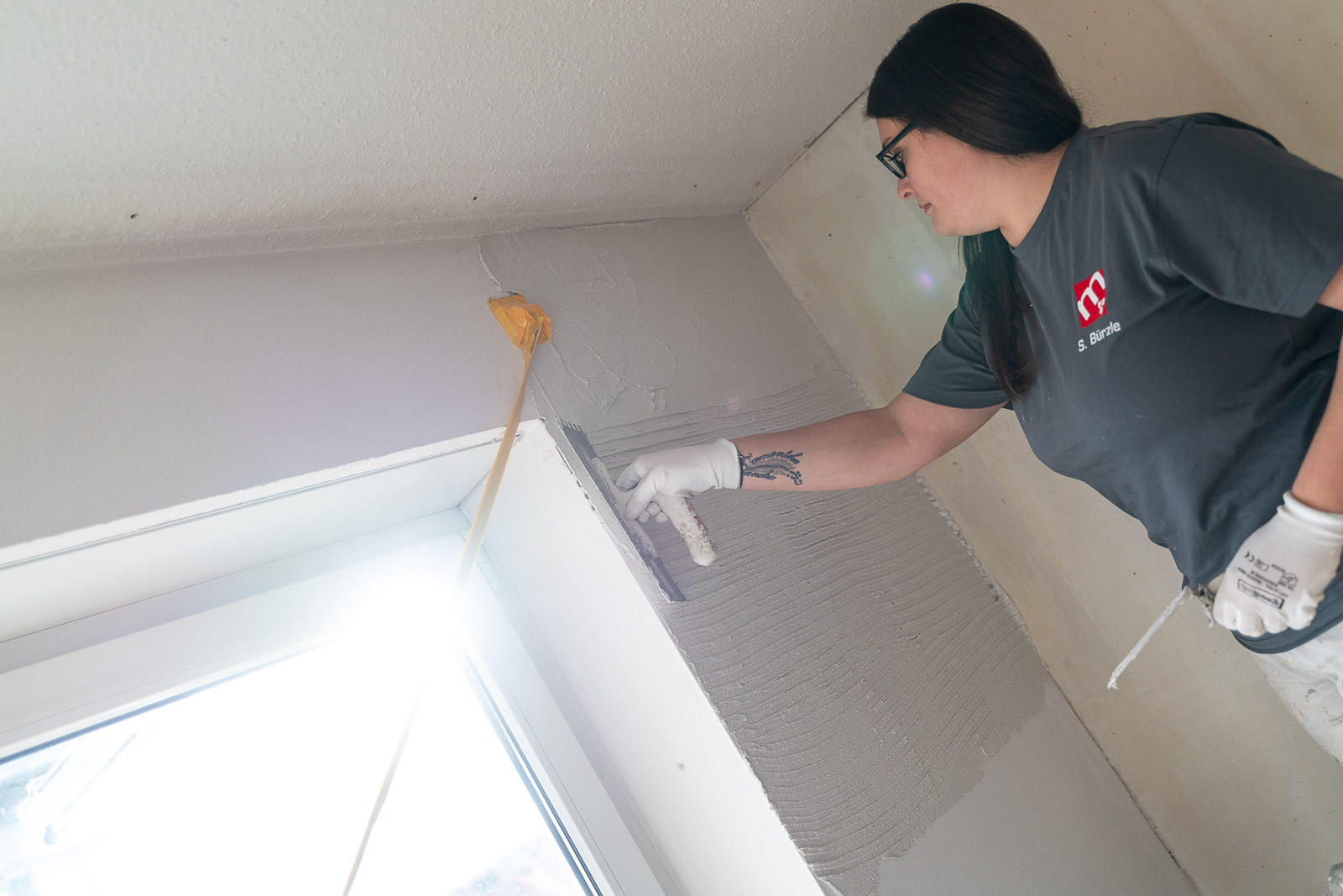  Eine Mitarbeiterin von Maler Merkle Illertissen verputzt fachgerecht eine Wand im Rahmen von Innenausbauarbeiten. 