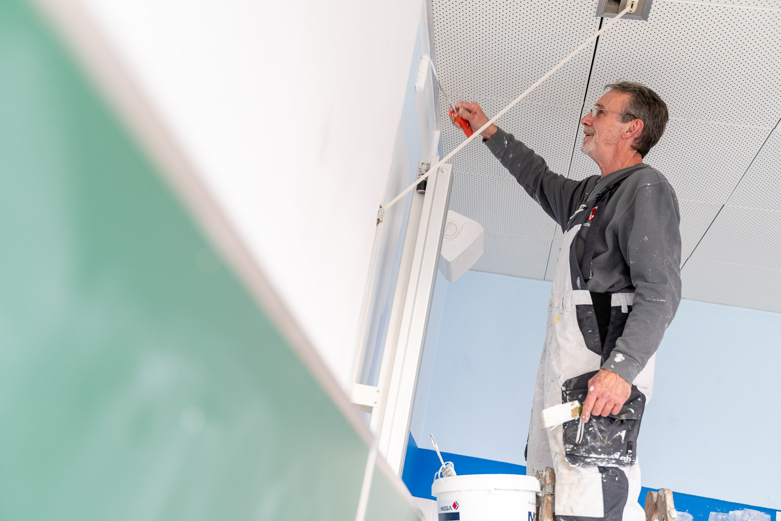 Ein Mitarbeiter von Maler Merkle Illertissen streicht die Wände in einer Schule professionell für den Innenausbau. 