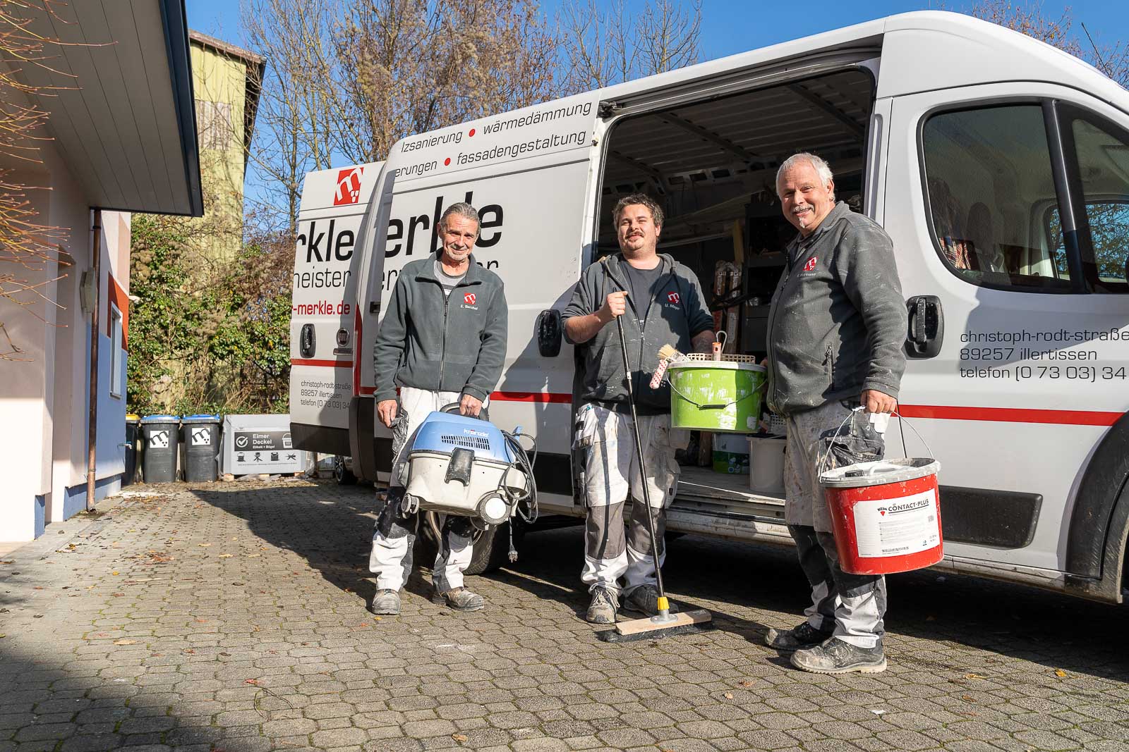  Drei Mitarbeiter von Maler Merkle Illertissen stehen vor dem Lieferwagen bereit für anstehende Maler- und Ausbauaufträge. 